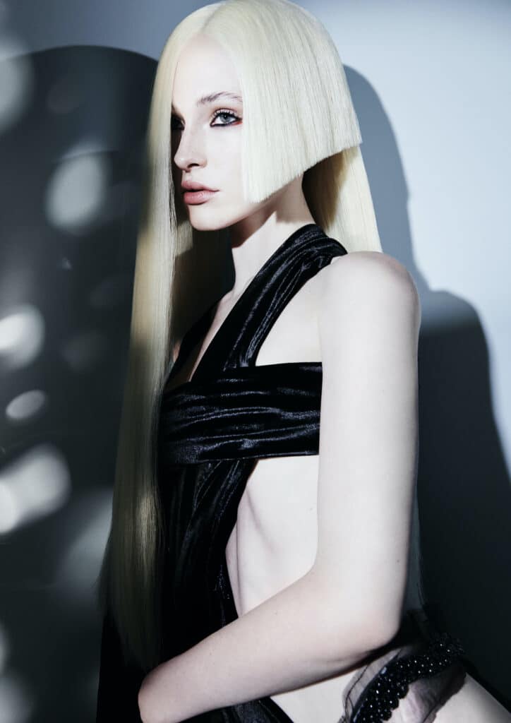 Woman with long blonde hair and a wedge cut out the side in a black halter neck top with a large cut-out at the side.